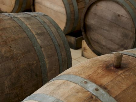 Wooden barrels aging wine or whiskey, arranged in rows. crafted staves, metal hoops, rustic cellar vibe.
