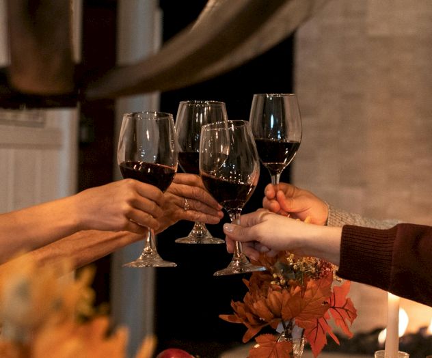 A toast is being clinked between two hands, beer pours into glasses as friends celebrate over drinks.