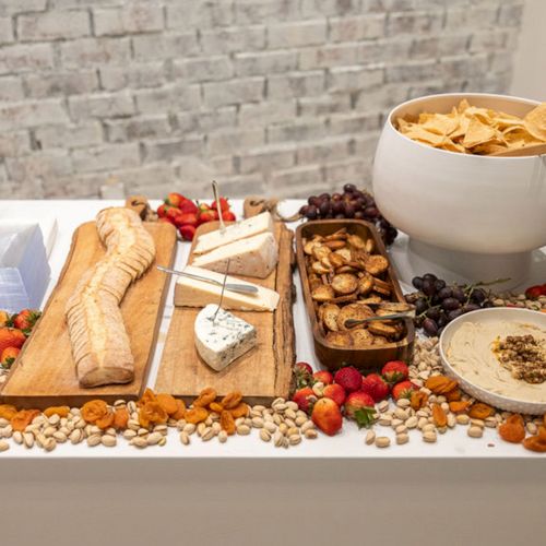 A spread of sandwiches, pastries, and drinks on a table with plates and napkins, ready for a meal.