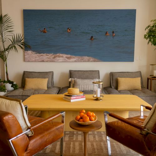 A cozy dining room with a long wooden table, chairs, warm lighting, plants, and a bright window&mdash;inviting and homey.