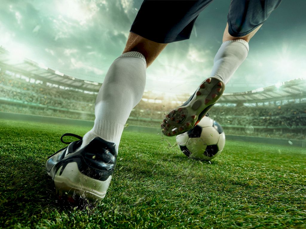 A soccer game in a stadium; a player kicks a ball on the green field.